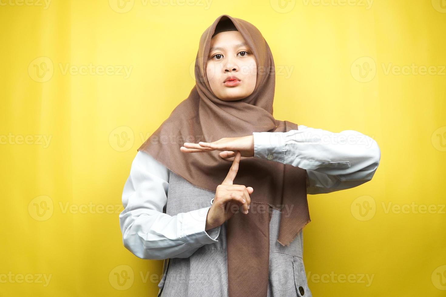 belle jeune femme musulmane asiatique avec la main montrant le panneau d'arrêt, la main silencieuse du signe, ne parle pas la main du signe, ne fait pas de bruit signe la main, isolée sur fond jaune photo