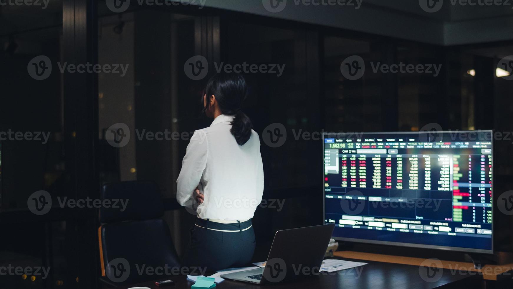 Jeune femme d'affaires chinoise millénaire travaillant tard dans la nuit avec un problème de recherche de projet sur un ordinateur portable dans la salle de réunion d'un petit bureau moderne. concept de syndrome d'épuisement professionnel des personnes d'asie. photo