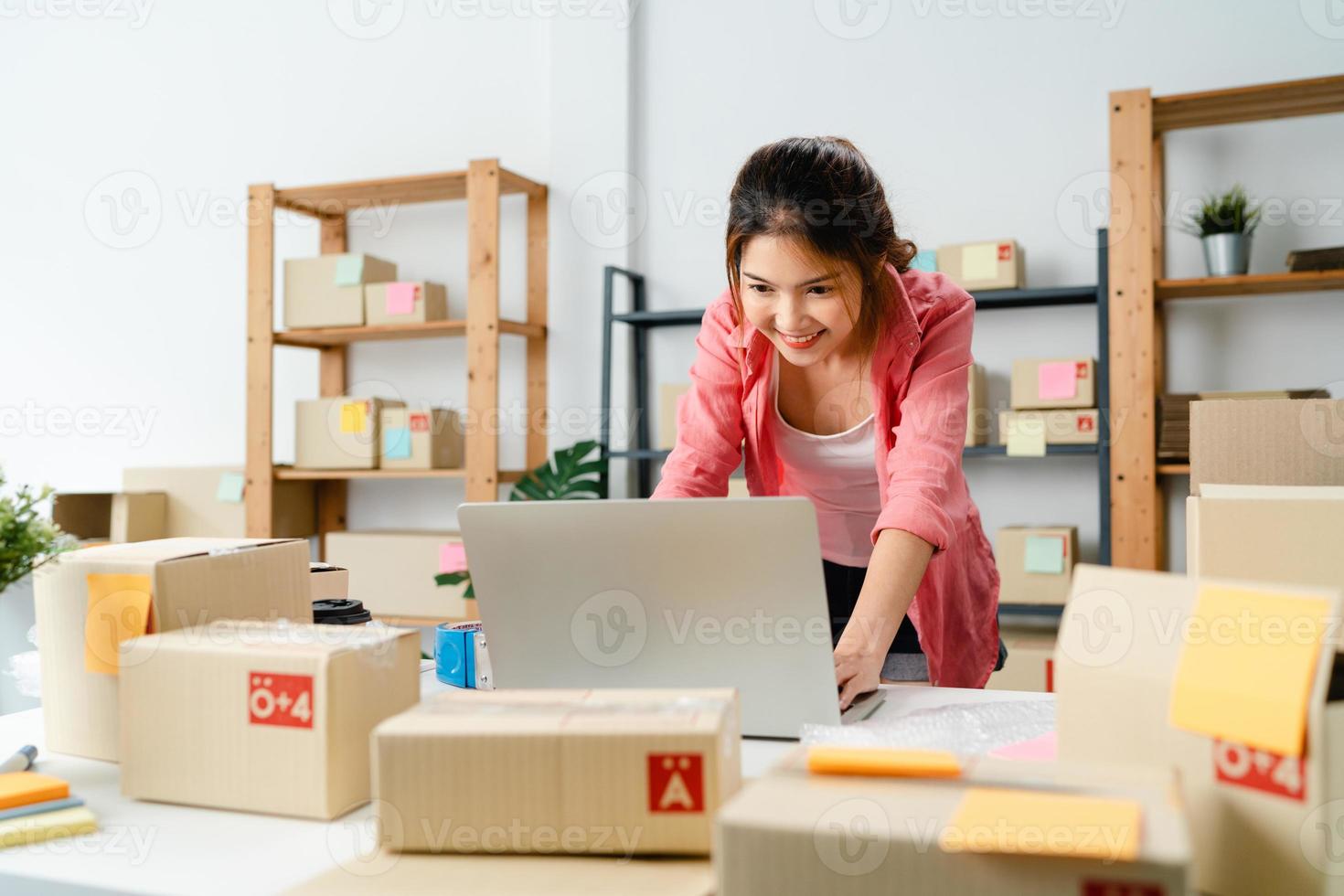 jeune femme d'affaires entrepreneur en Asie vérifie le bon de commande du produit en stock et enregistre le travail sur ordinateur portable au bureau à domicile. propriétaire de petite entreprise, livraison sur le marché en ligne, concept de style de vie indépendant. photo