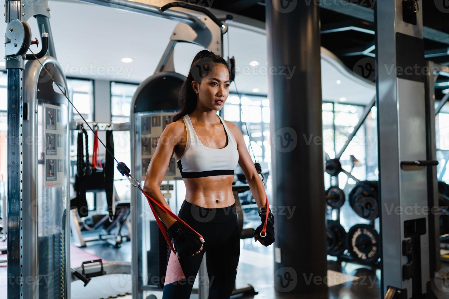Jeune femme asiatique faisant de l'exercice en faisant de l'exercice avec un câble croisé de la machine pour brûler les graisses en cours de fitness. athlète avec six pack, activité récréative sportive, entraînement fonctionnel, mode de vie sain. photo