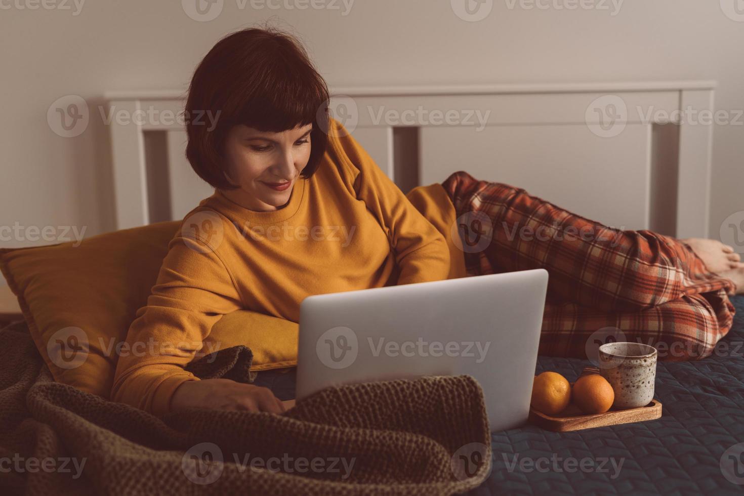 travail à domicile, enseignement à distance, surfer sur Internet au crépuscule. femme mature photo