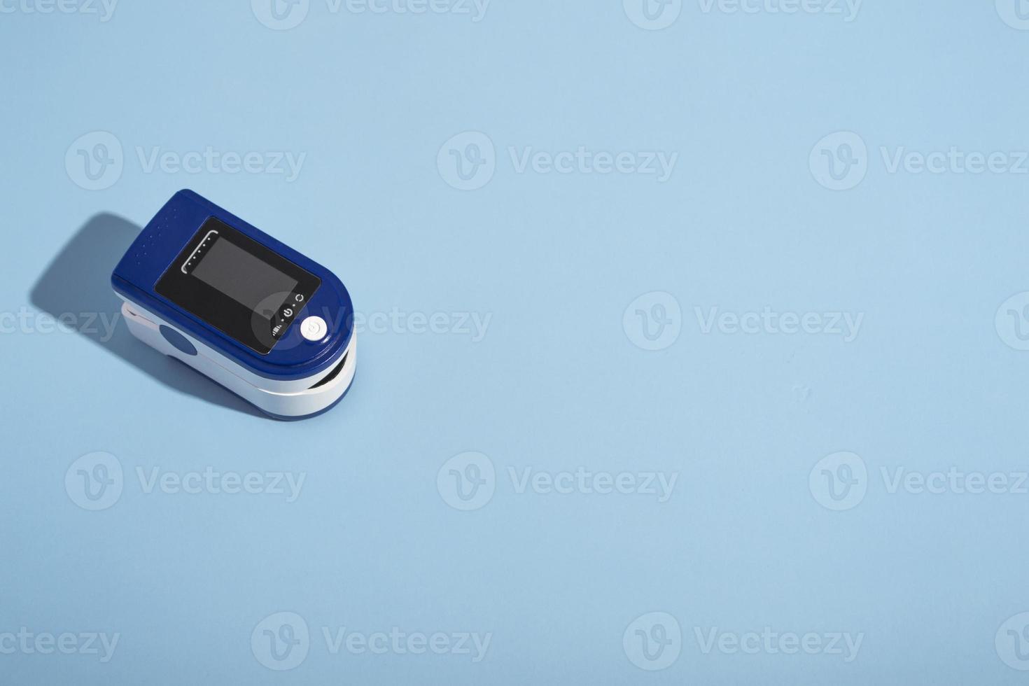 oxymètre de pouls portable sur fond bleu avec une ombre dure. contrôle de l'oxygène dans les poumons. vue d'en-haut photo