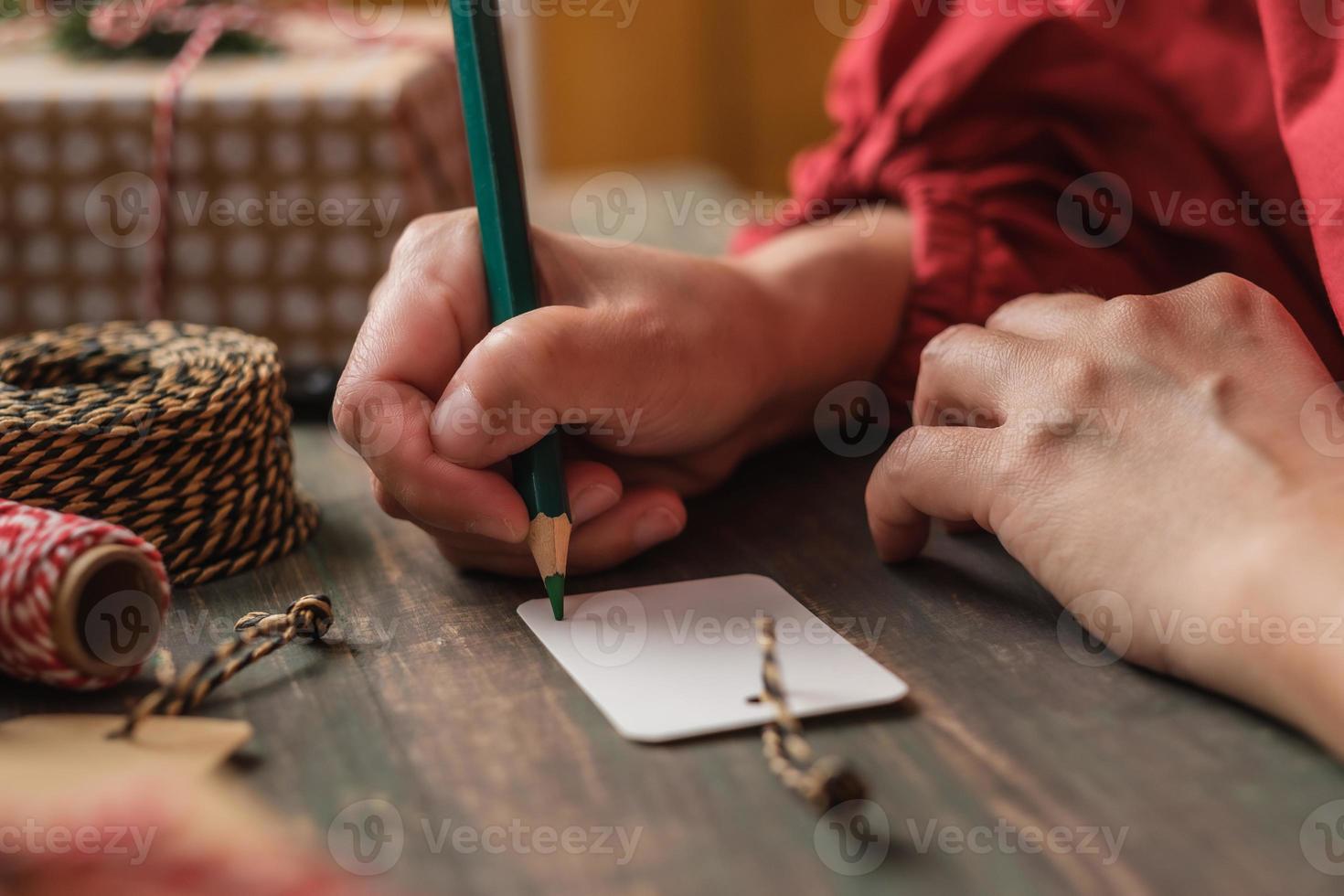 Femme écrivant une étiquette-cadeau et attachez-la au cadeau de Noël sur une table en bois photo