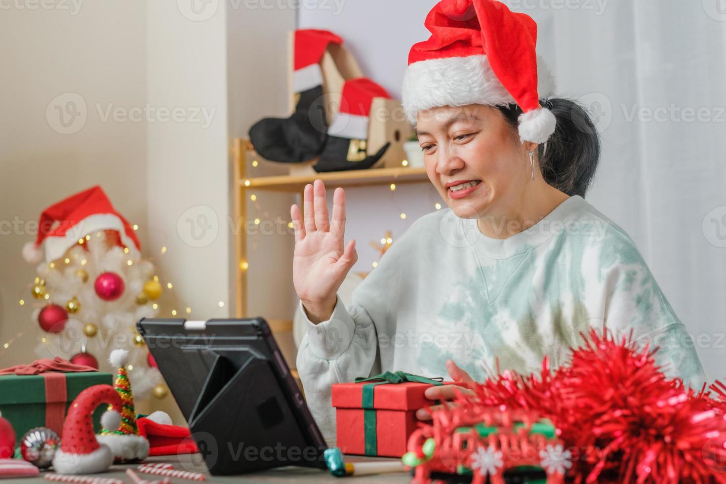 une femme asiatique célèbre le nouvel an et la fête de noël avec des amis d'appel vidéo sur tablette à la maison photo