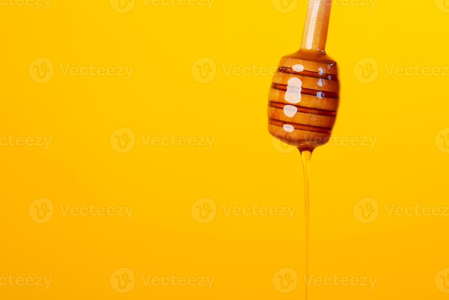 Gouttes de miel d'une cuillère de miel sur fond jaune photo