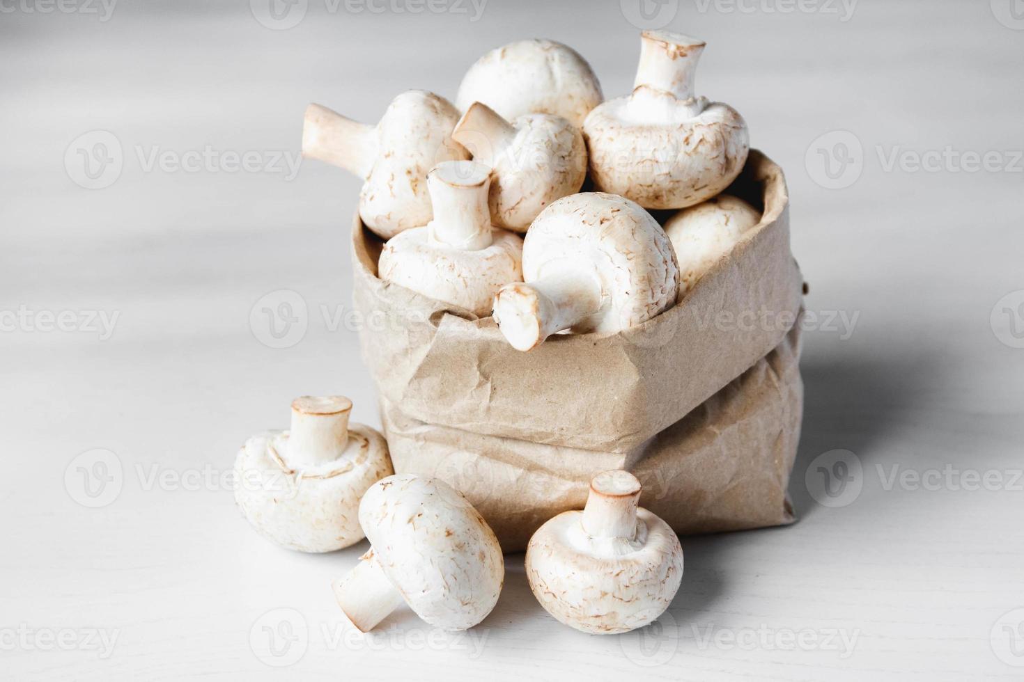 champignons champignons dans un sac en papier sur une table en bois blanc photo