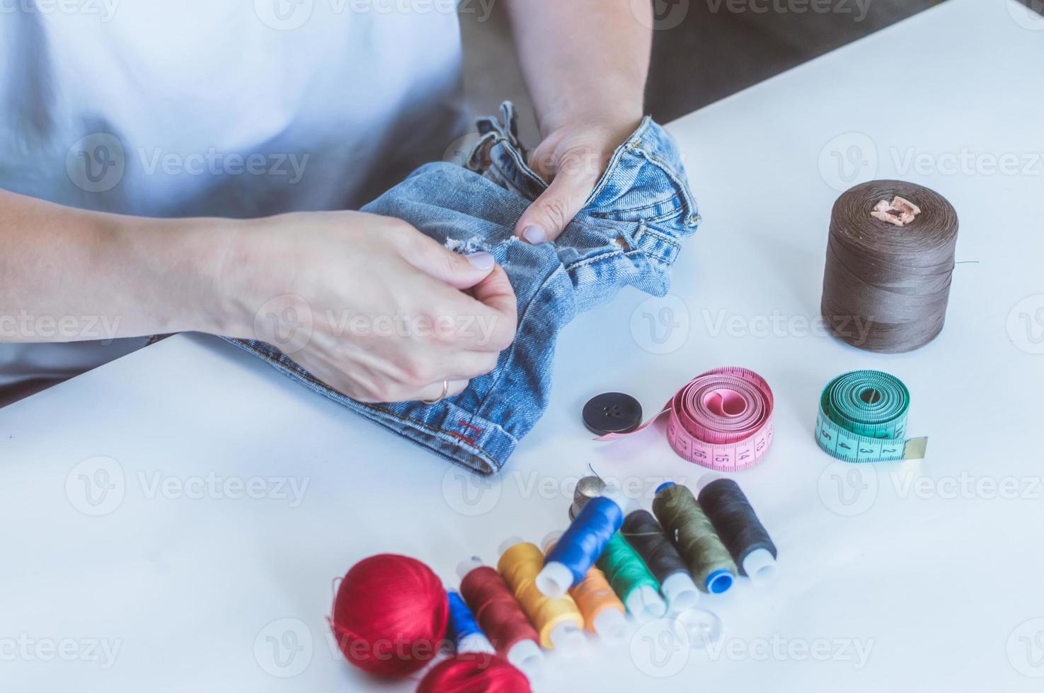 les mains des femmes, un tailleur coud des vêtements à une table sur laquelle reposent des bobines de fil photo