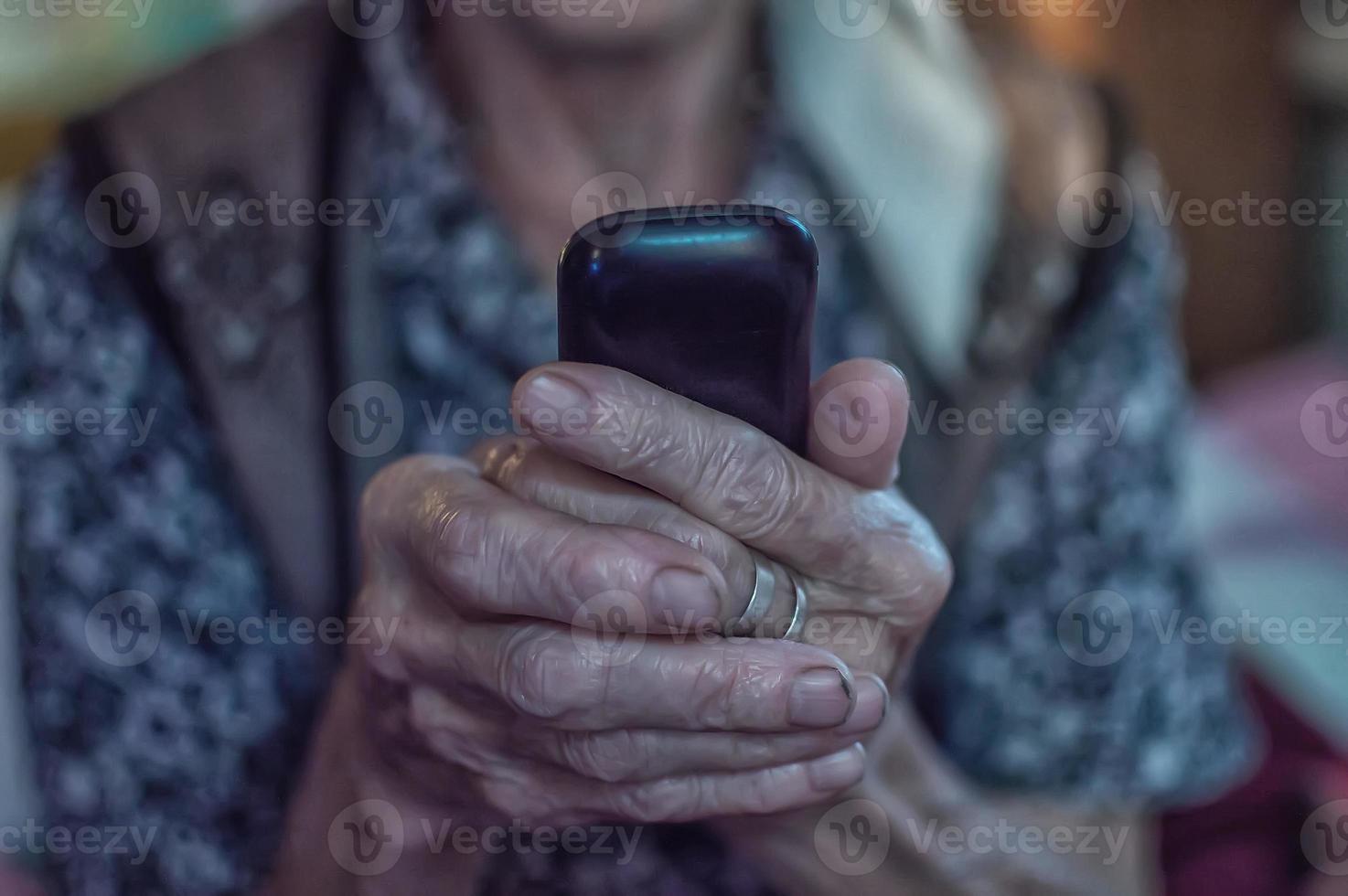 vieille femme dans un foulard avec un vieux téléphone dans une maison de retraite. fermer. photo