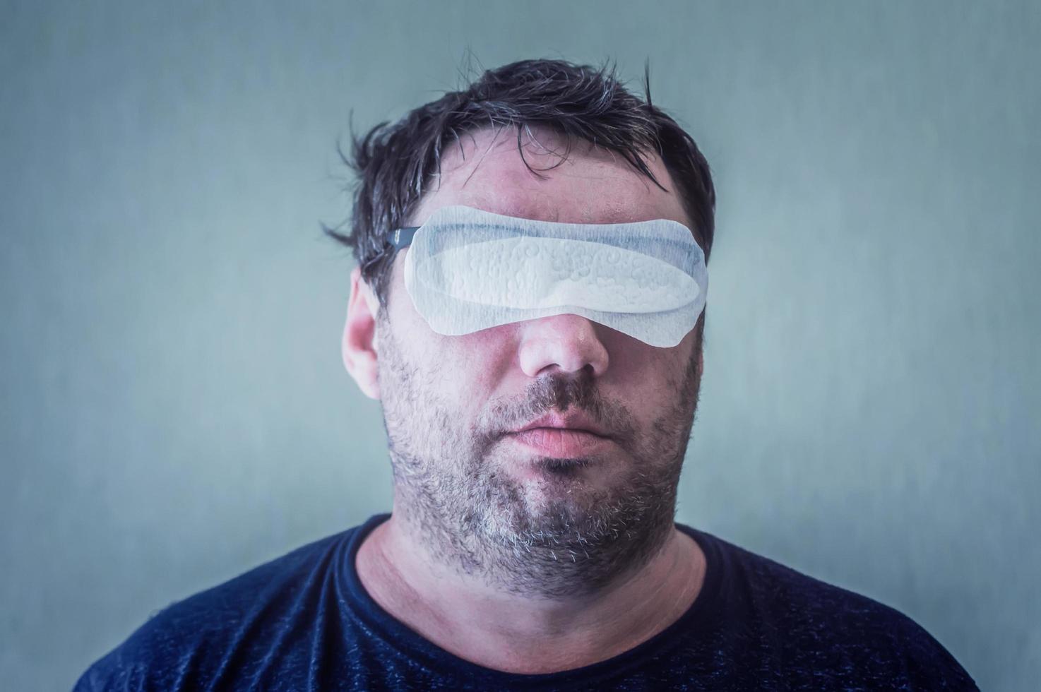 un homme avec une serviette hygiénique féminine sur le visage, avec des yeux sur la surprise, concept photo