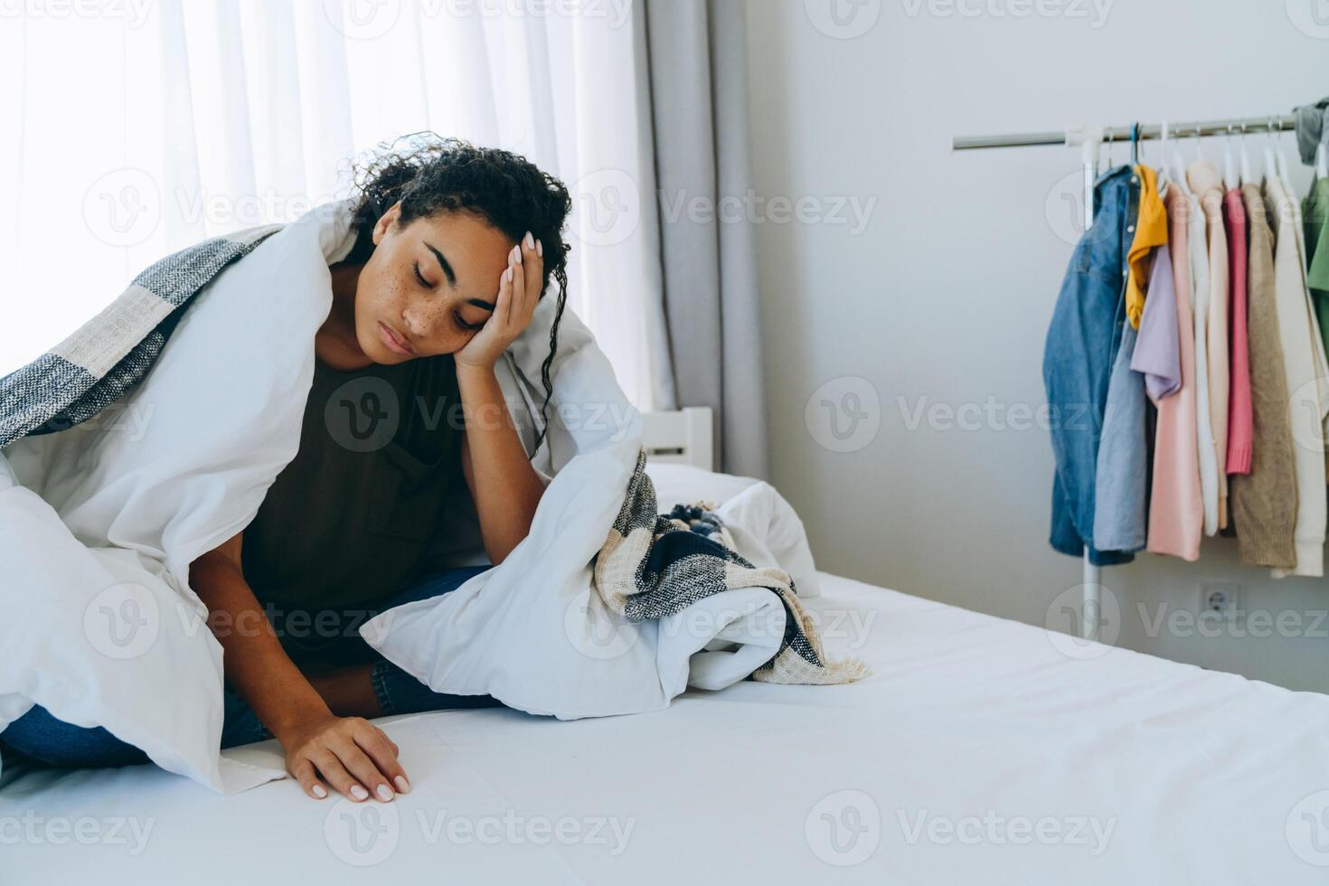 femme afro-américaine endormie s'est enveloppée dans une couverture sur le lit photo