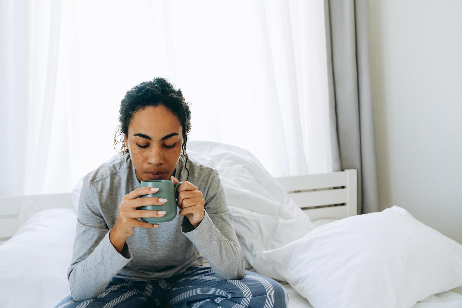 femme africaine buvant du café sur le lit photo