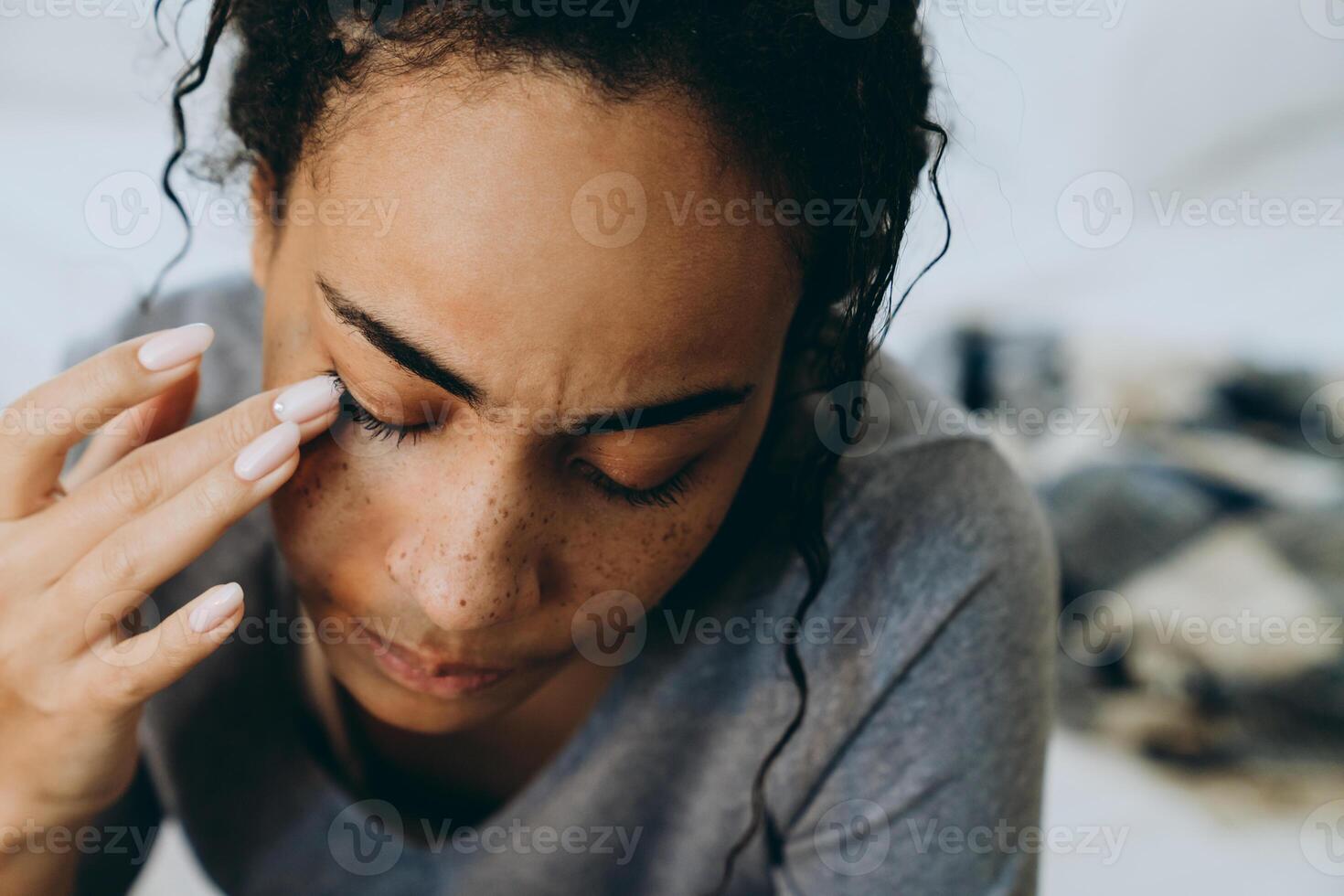 jeune femme noire pleurant et essuyant ses larmes alors qu'elle était assise sur le lit photo