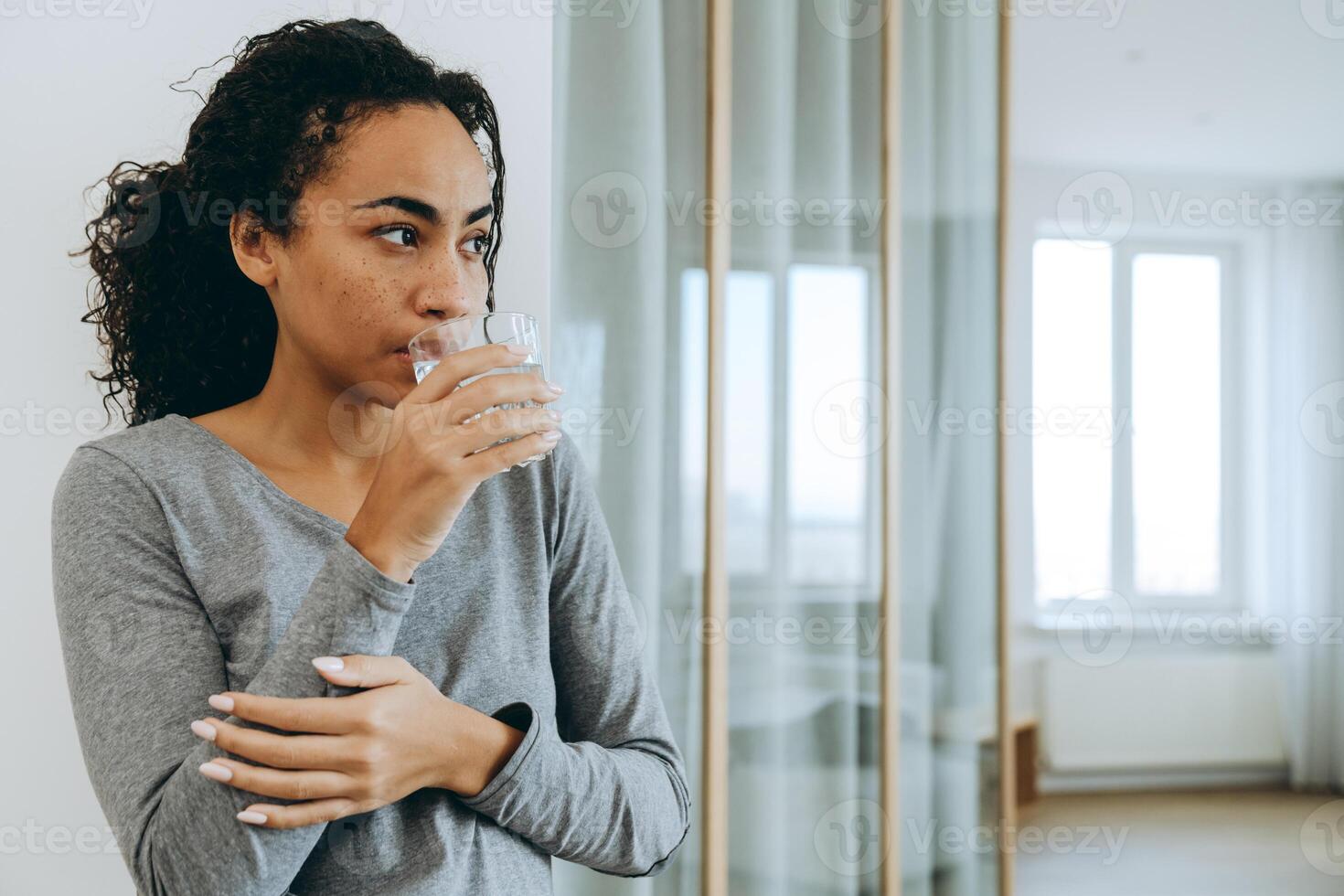 jeune femme noire buvant de l'eau pendant qu'elle passe du temps à la maison photo