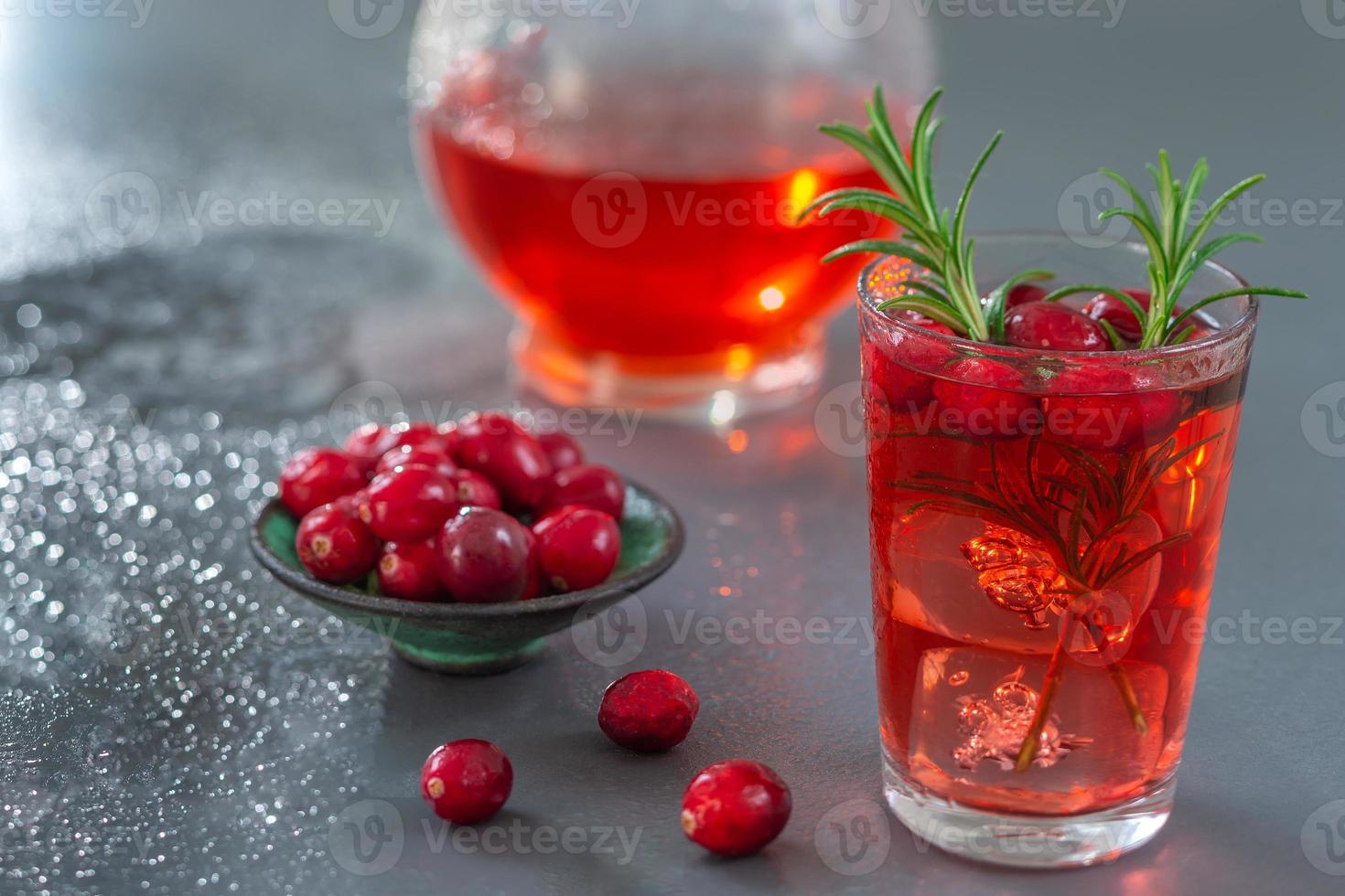 verre de jus de fruits frais canneberges bio jus bio santé au romarin, pichet, sur fond d'ardoise grise photo