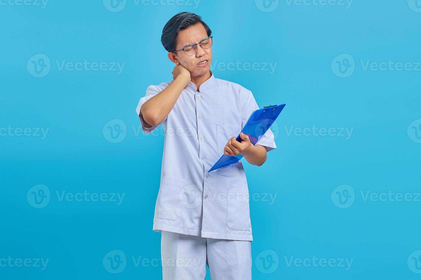 portrait d'un infirmier tenant un presse-papiers et ayant l'air fatigué du travail toute la journée sur fond bleu photo