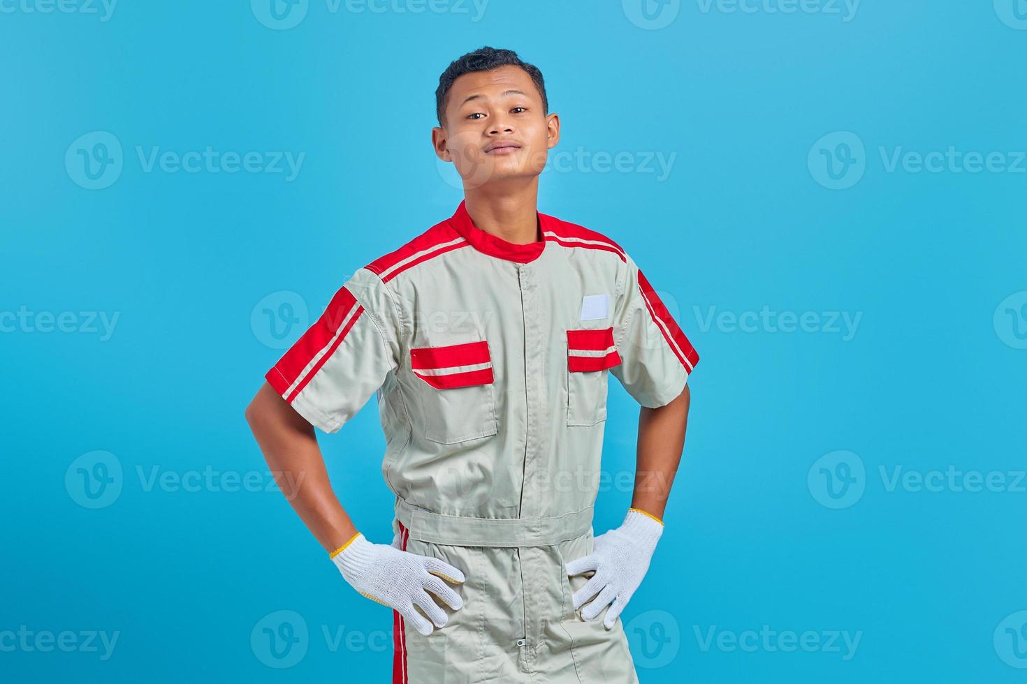 Portrait de jeune mécanicien asiatique séduisant tenant la main avec confiance sur fond bleu photo