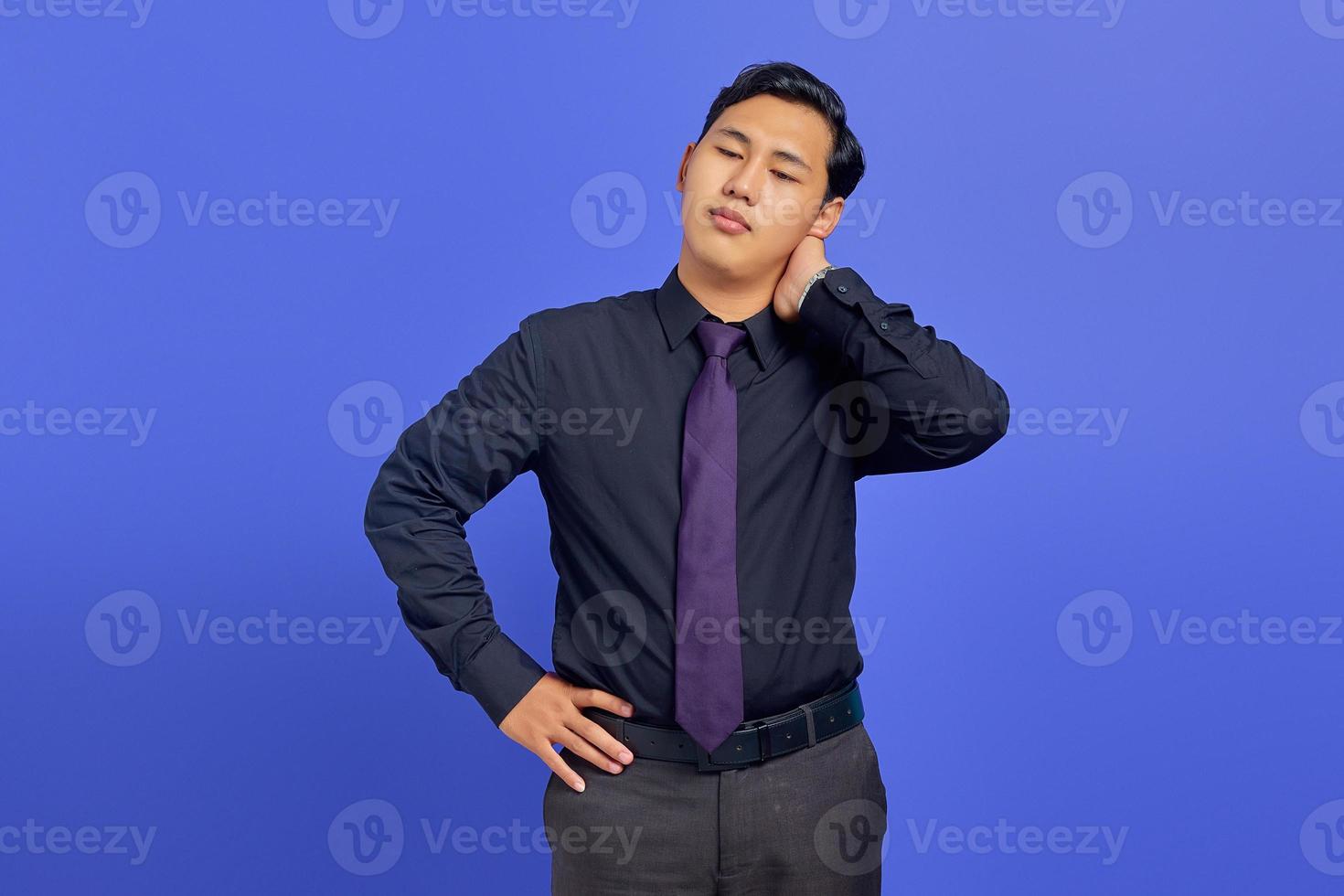 beau jeune homme d'affaires fatigué après une longue journée de travail sur fond violet photo