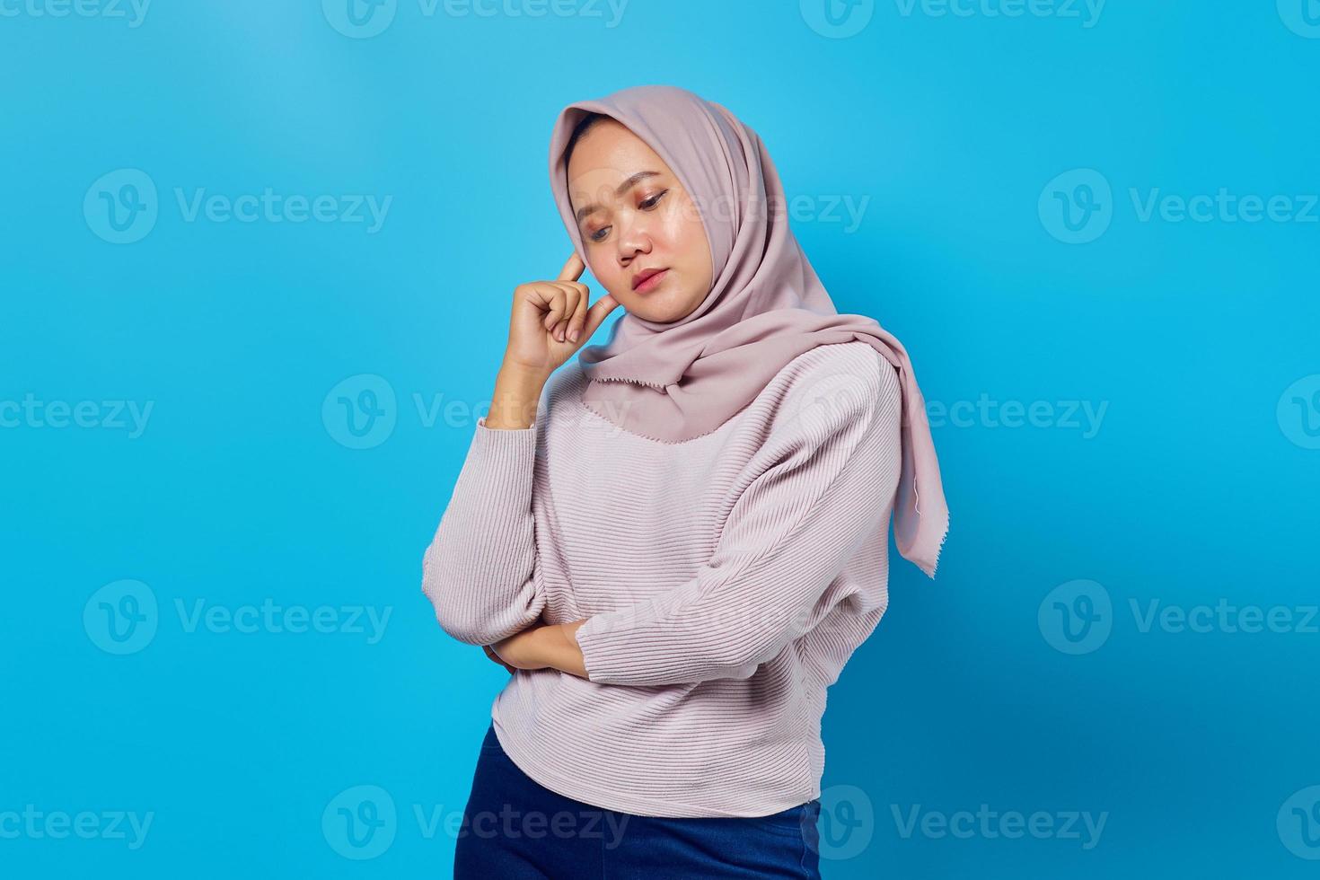 Portrait d'une belle femme asiatique pensant aux doutes isolés sur fond bleu photo