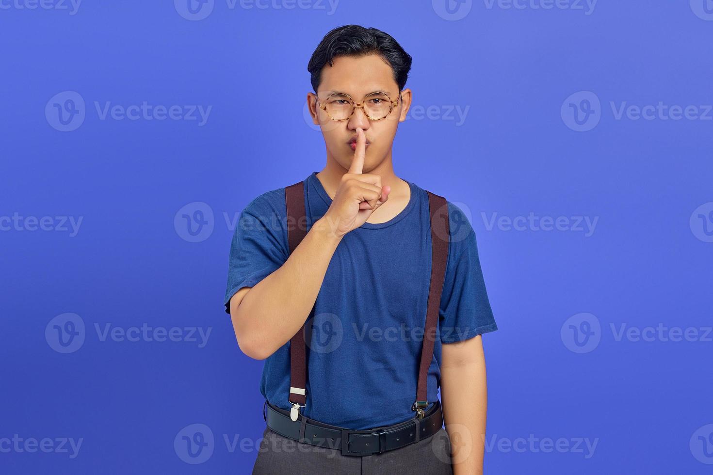 doigt d'homme séduisant sur les lèvres et faisant un mouvement silencieux sur fond violet photo