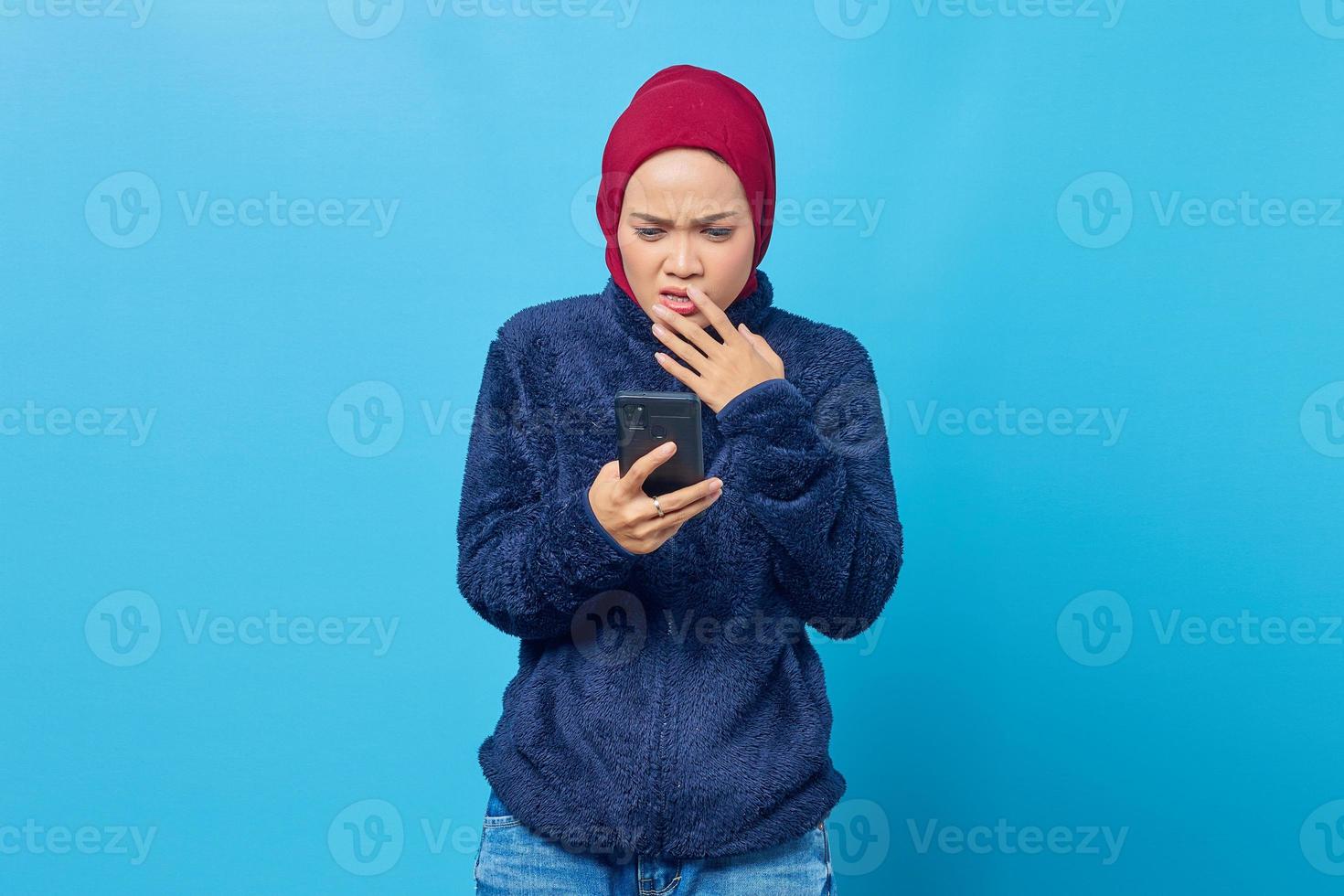 jeune femme asiatique tenant un smartphone a l'air anxieuse et inquiète de peur de quelque chose photo