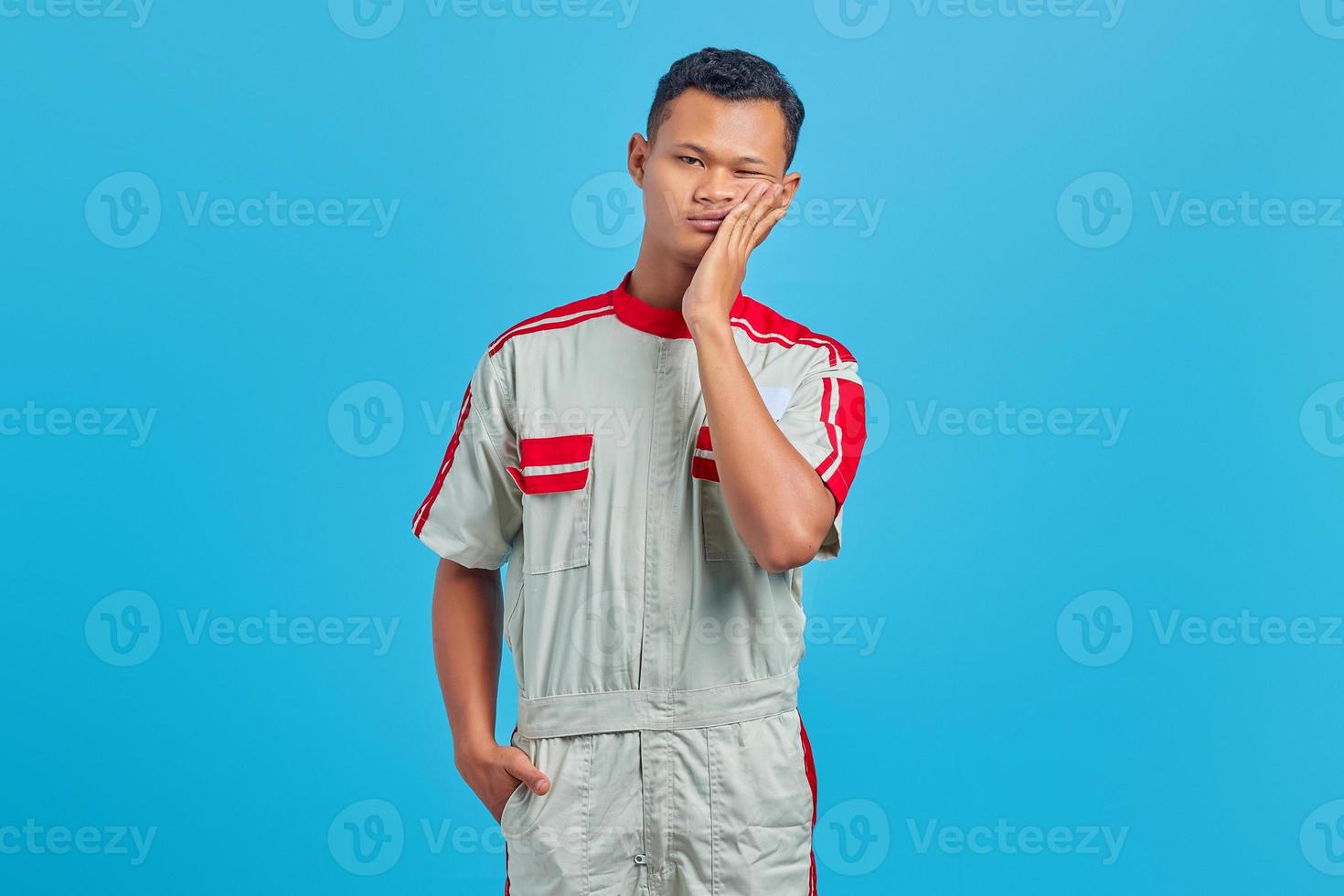 portrait de jeune mécanicien asiatique touchant la bouche avec une expression douloureuse sur fond bleu photo