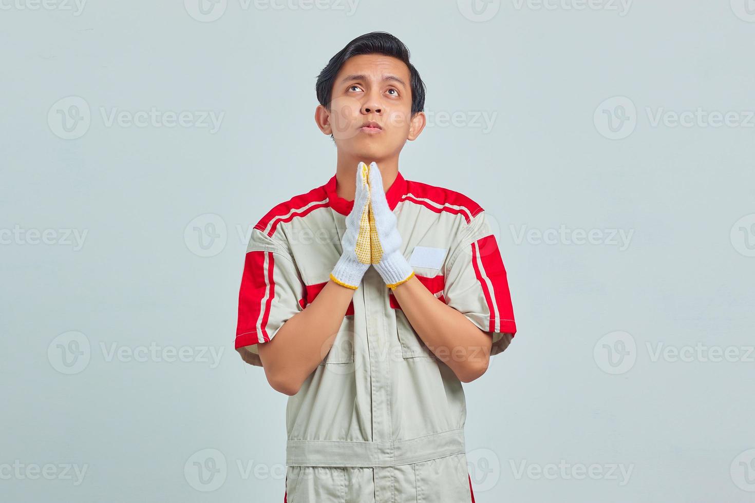 portrait d'un beau jeune mécanicien plaidant et priant avec les mains avec une expression d'espoir sur un visage très émotif et inquiet photo