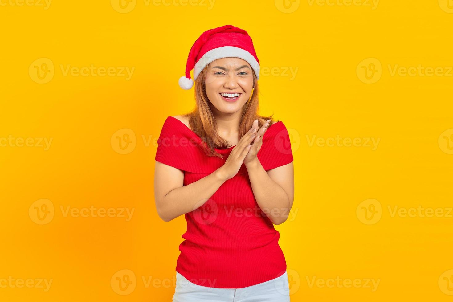jeune femme souriante portant un chapeau de noël et applaudissant après la présentation lors d'une conférence sur fond jaune photo