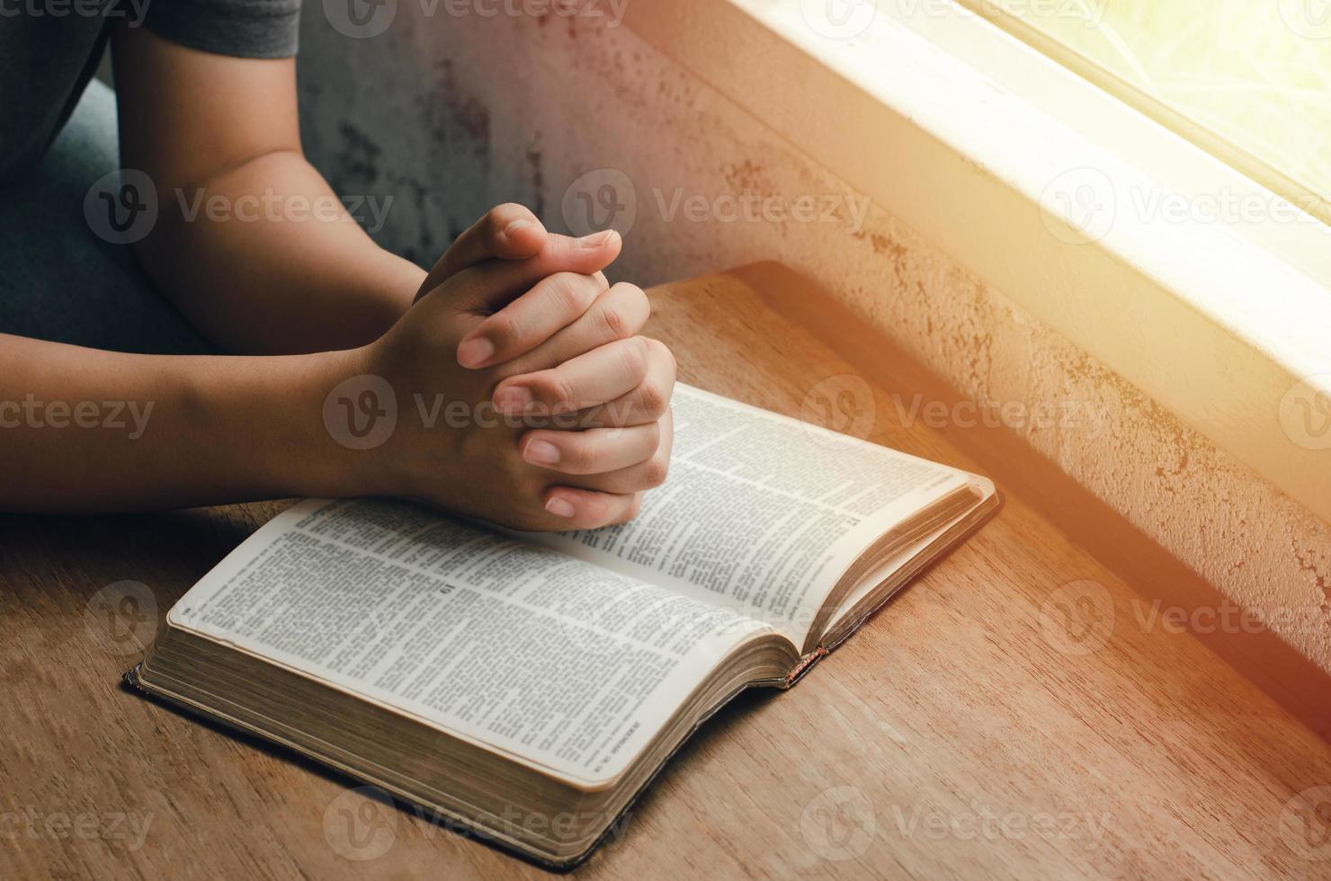 fille assise et priant pour les bénédictions de dieu avec la bible les mains jointes dans la prière biblique, spirituelle et religieuse, communiquer, parler à dieu. amour et pardon photo