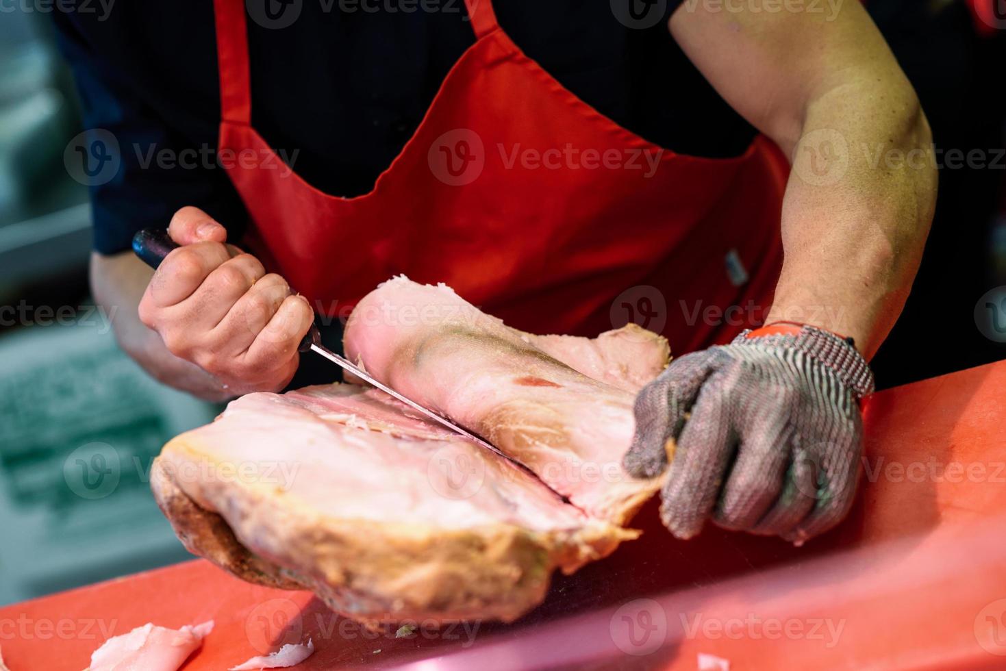 Boucher désossant un jambon dans une boucherie moderne photo