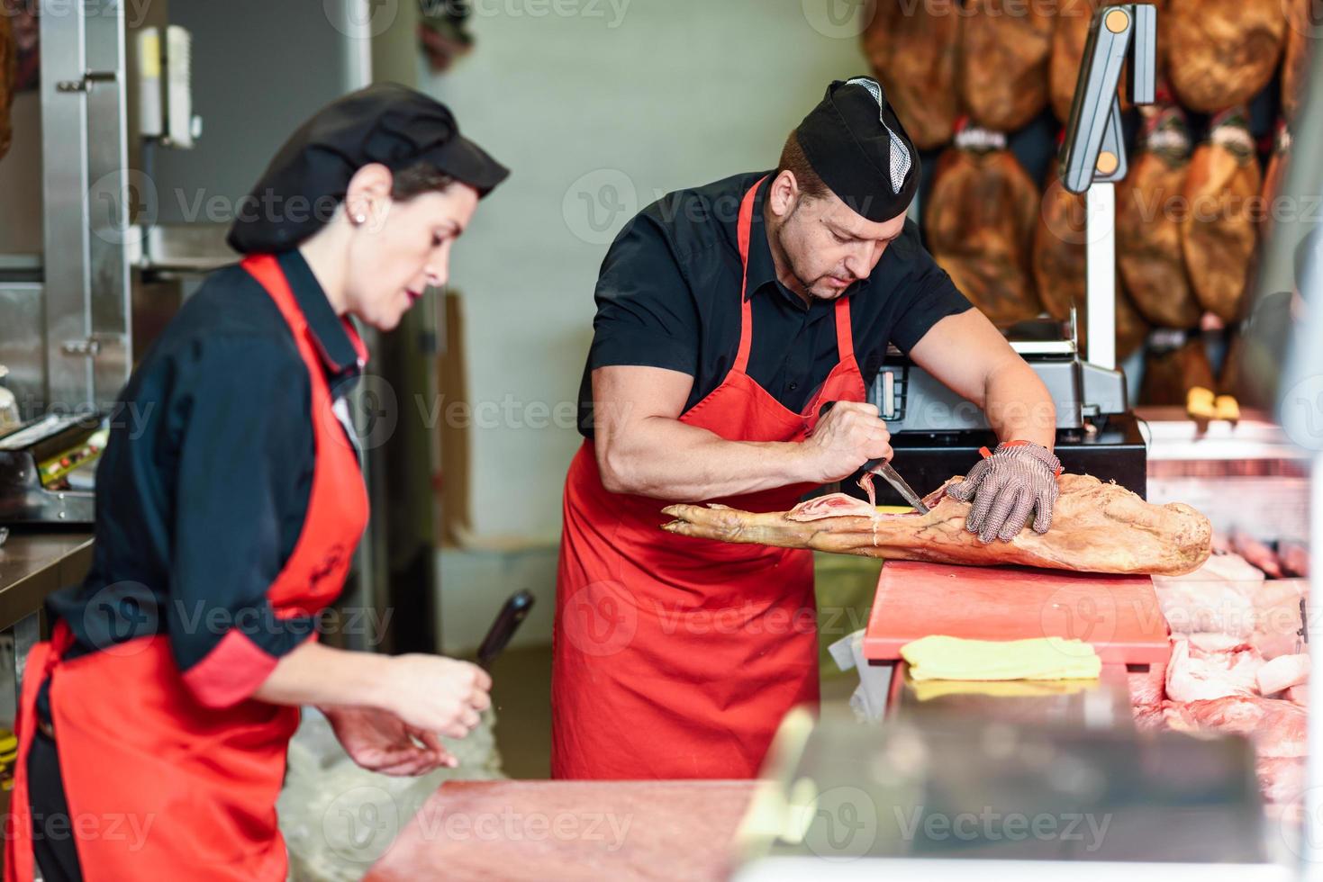 Bouchers désossant un jambon dans une boucherie moderne photo