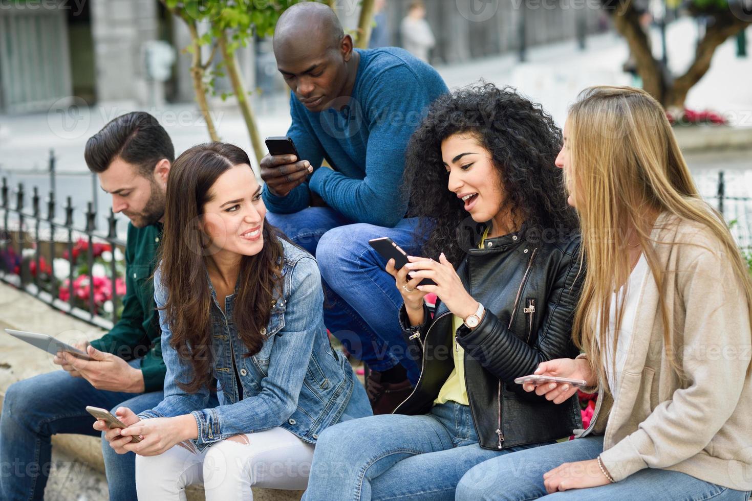 jeunes multiethniques utilisant des smartphones et des tablettes à l'extérieur photo