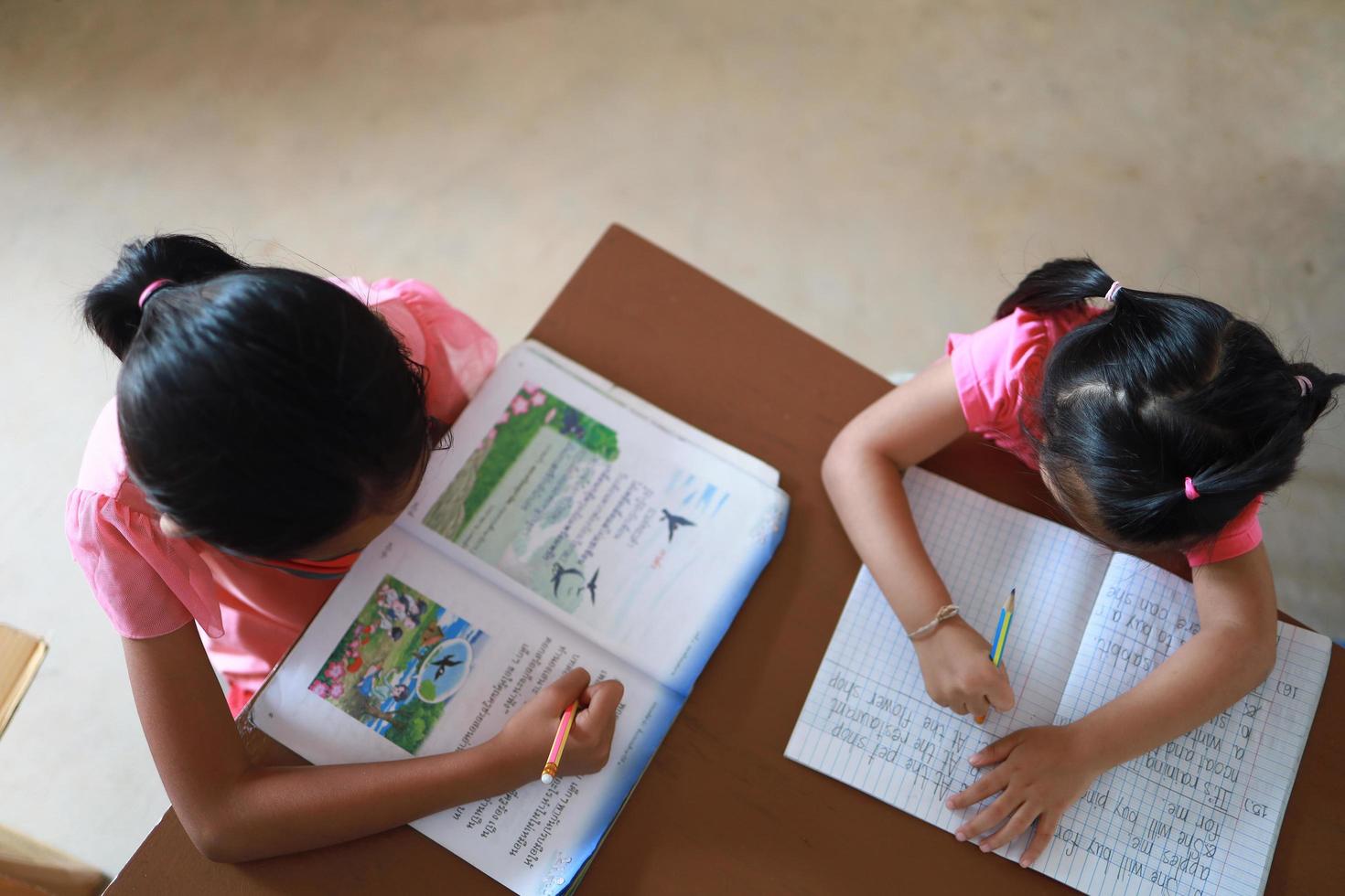 une jolie fille asiatique fait ses devoirs dans sa maison pendant la journée photo