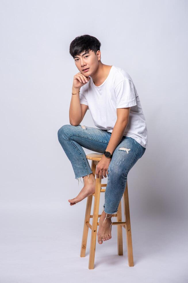 un jeune homme en t-shirt blanc est assis sur une chaise haute. photo