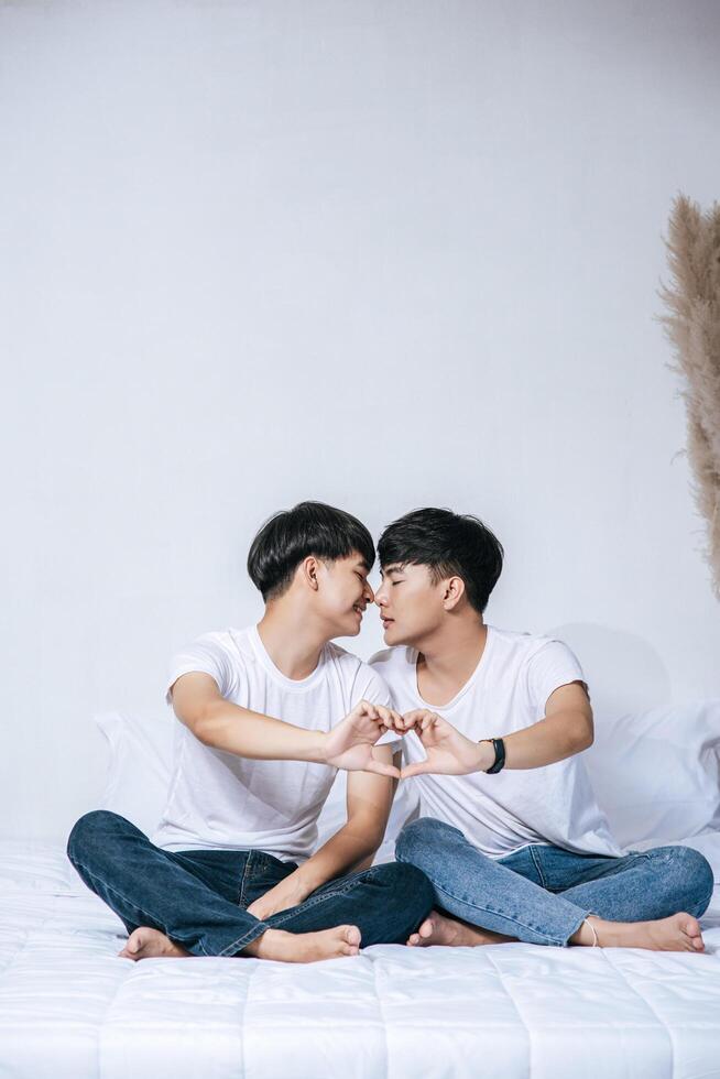 deux jeunes hommes aimants se regardent et font une main de symbole d'amour. photo
