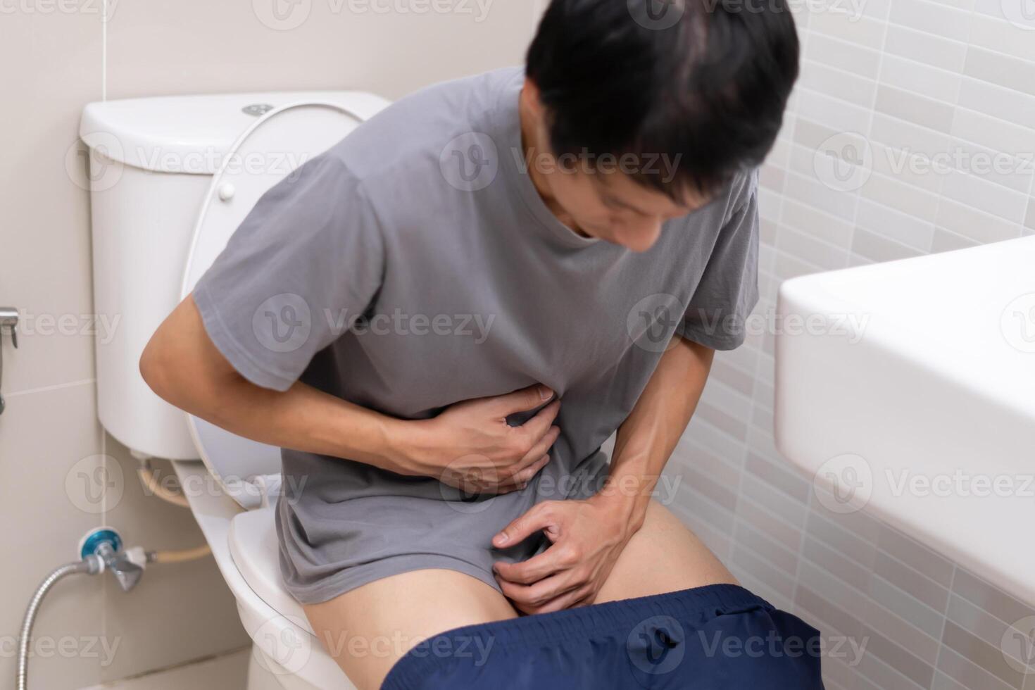 constipation et la diarrhée dans salle de bains. blesser homme toucher ventre estomac mal douloureux. côlon inflammation problème, toxique nourriture, abdominal douleur, abdomen, constipé dans toilettes, maux d'estomac, hygiène photo