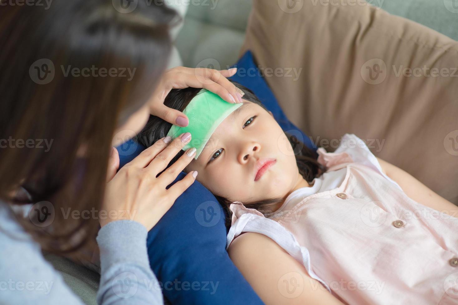 une mère asiatique prend soin de son enfant qui a de la fièvre et des maladies à la maison. photo