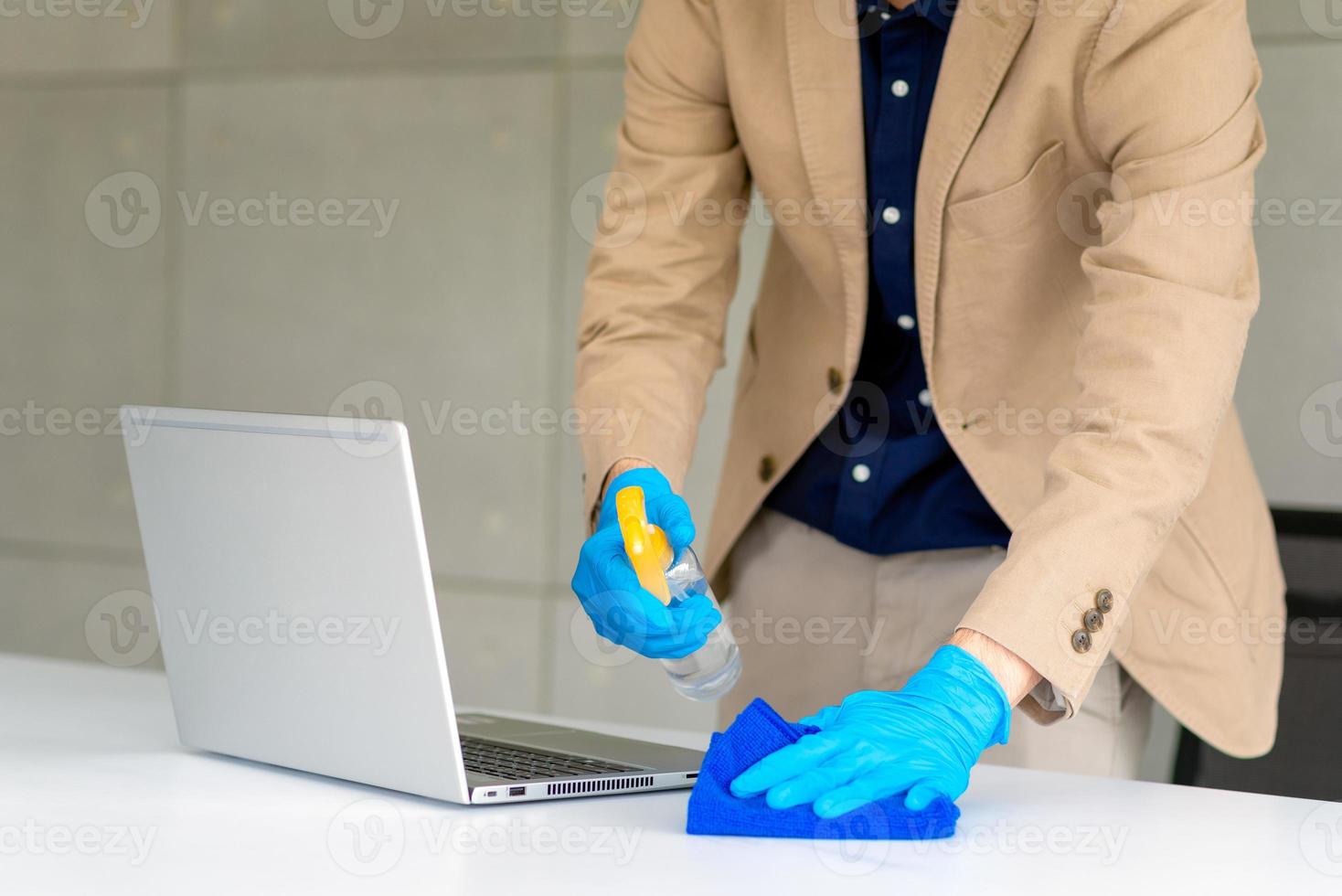 homme d'affaires portant un masque et utilisant un désinfectant personnel pour nettoyer son bureau afin de maintenir l'hygiène.préventif pendant la période d'épidémie de coronavirus ou de covid19. photo