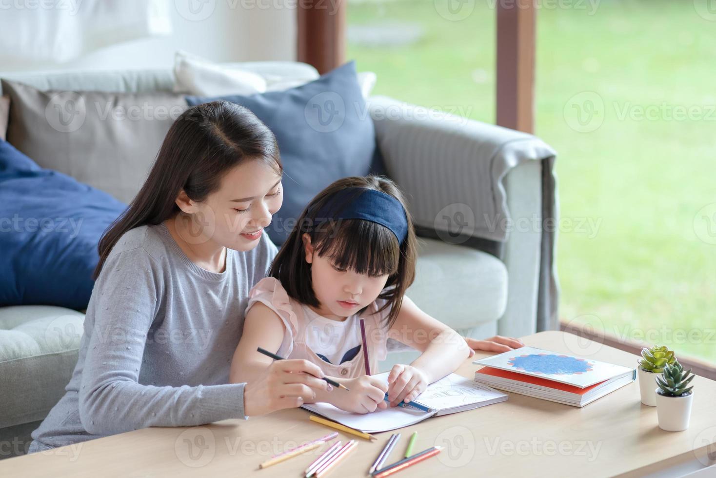 une mère asiatique apprend à sa jolie fille à étudier dans le salon à la maison photo
