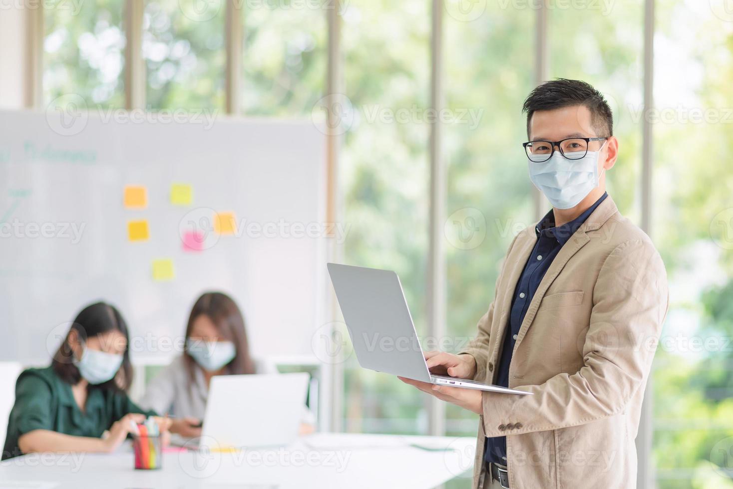 les employés de l'entreprise portant un masque pendant le travail au bureau pour maintenir l'hygiène suivent la politique de l'entreprise. préventif pendant la période d'épidémie de coronavirus ou de covid19. photo