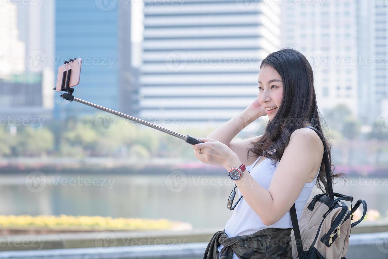 belle femme de tourisme asiatique prenant des selfies sur un smartphone dans le centre-ville urbain. voyage de vacances en été. photo