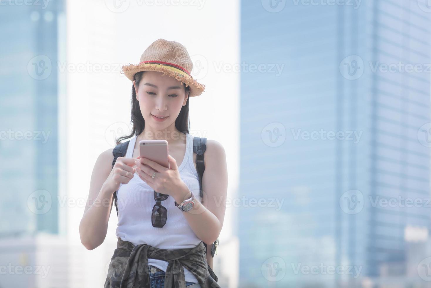 belle femme de tourisme solo asiatique souriante et regardant un téléphone portable pour rechercher un site touristique de touristes. voyage de vacances en été photo