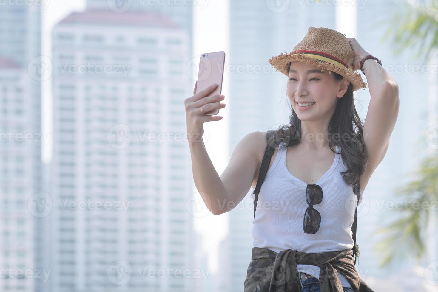 belle femme de tourisme asiatique prenant des selfies sur un smartphone dans le centre-ville urbain. voyage de vacances en été. photo