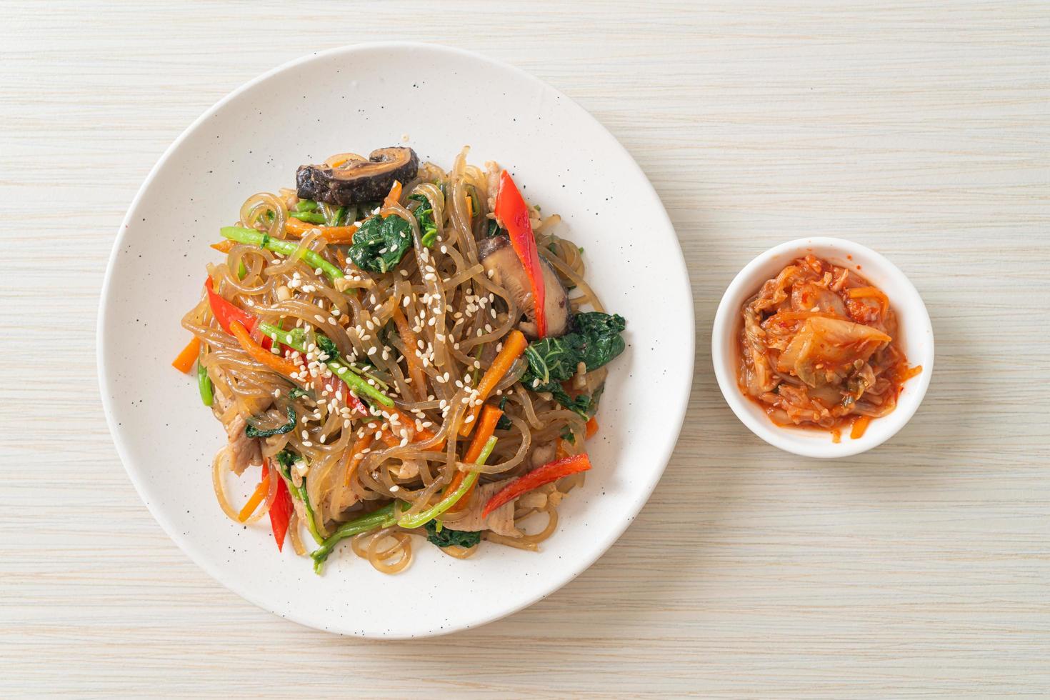 nouilles japchae ou vermicelles coréennes sautées aux légumes et au porc garnies de sésame blanc photo