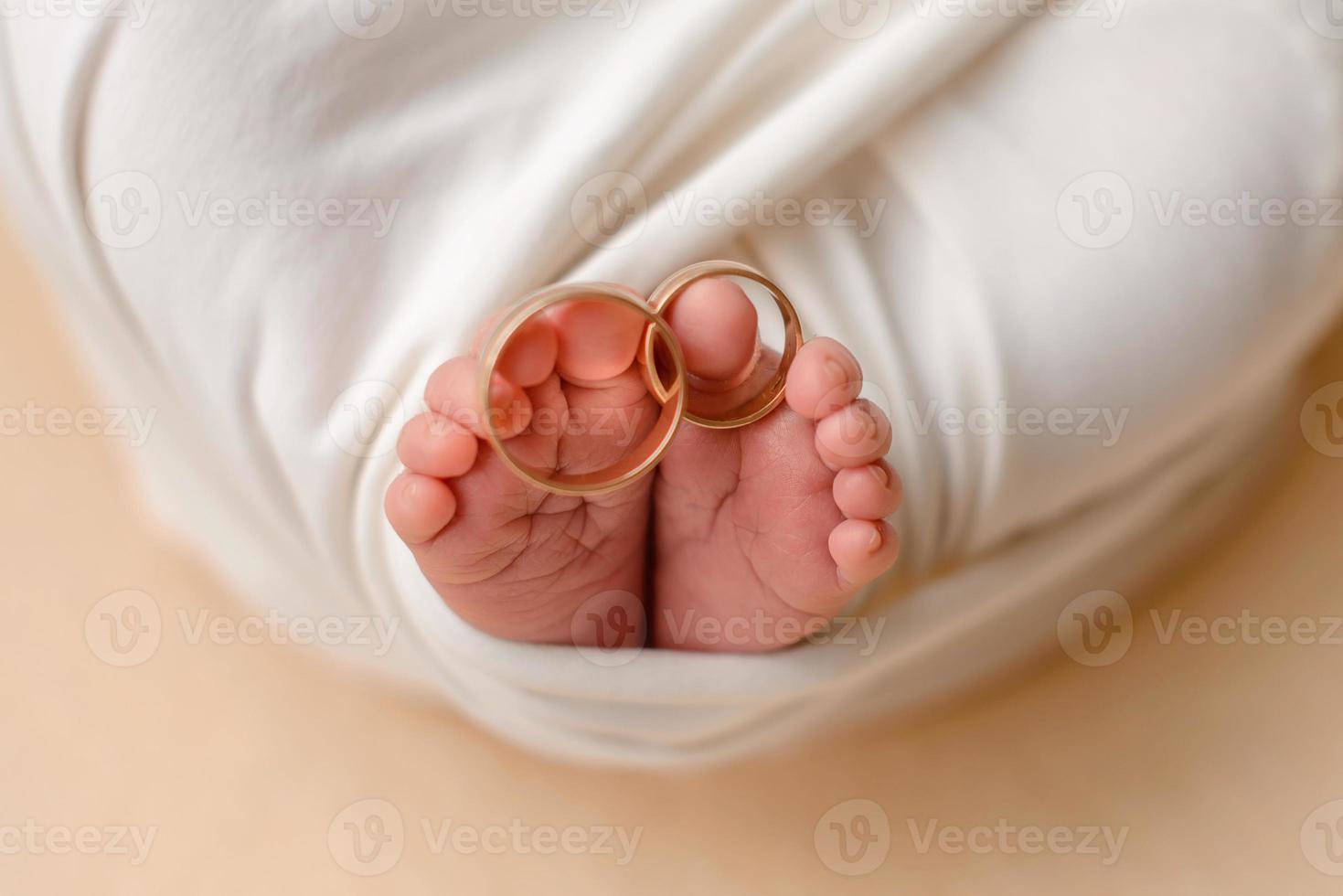 petits pieds d'un nouveau-né avec les alliances de ses parents aux doigts photo