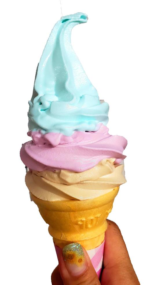 motif de dessert glacé à saveur arc-en-ciel de crème glacée dans une main de cône de gaufre marron tenant sur blanc. photo