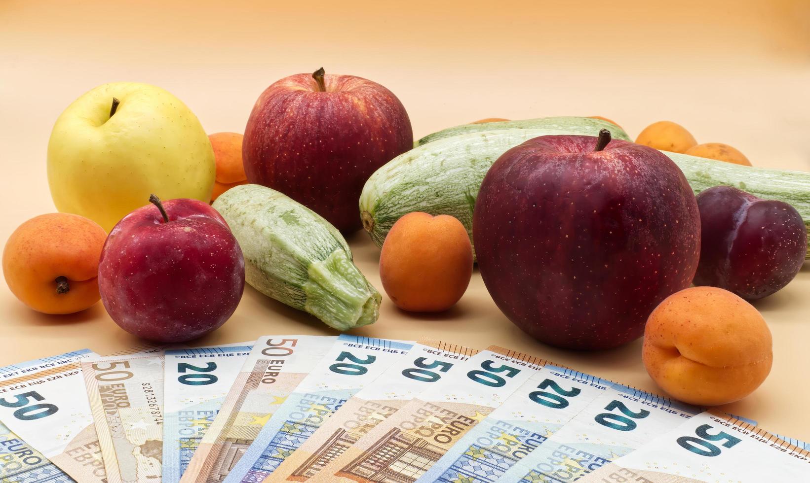 fruits et légumes et une pile de billets en euros. concept de coût des fruits et légumes photo