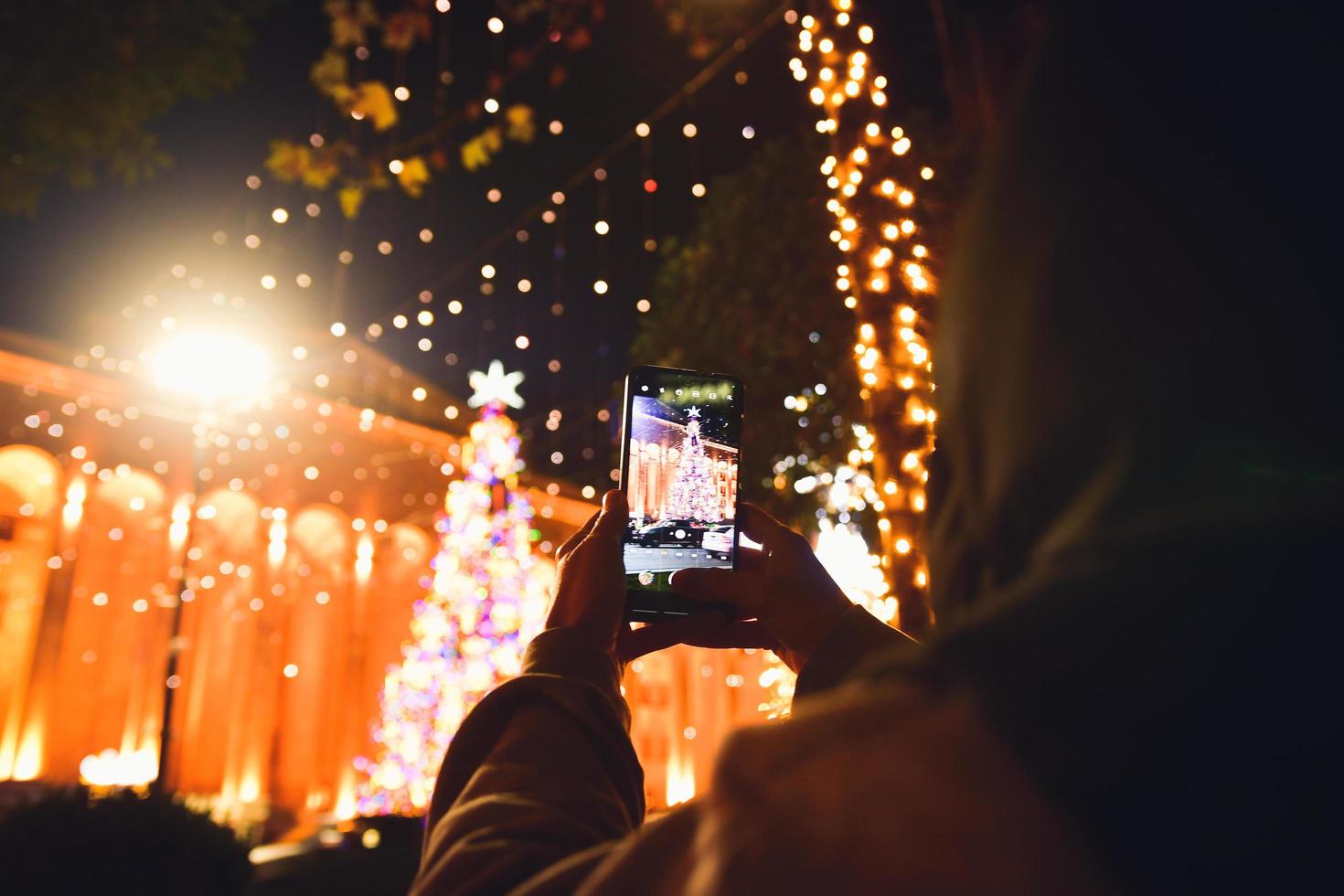 un touriste prend une photo d'un arbre de Noël
