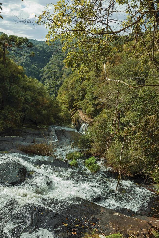 cascade tombant sur des rochers au milieu d'une forêt luxuriante par temps nuageux au parc caracol près de canela. une charmante petite ville très appréciée par son écotourisme dans le sud du brésil. photo