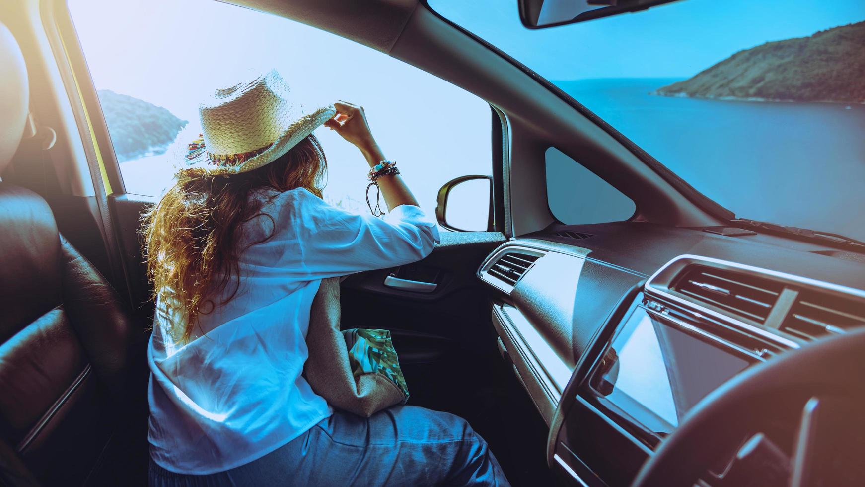 femme conduire un voyage en voiture se détendre à la plage pendant les vacances d'été. en regardant par la fenêtre de la voiture pour voir les magnifiques montagnes et le paysage marin. cap promthep, phuket, thaïlande. photo