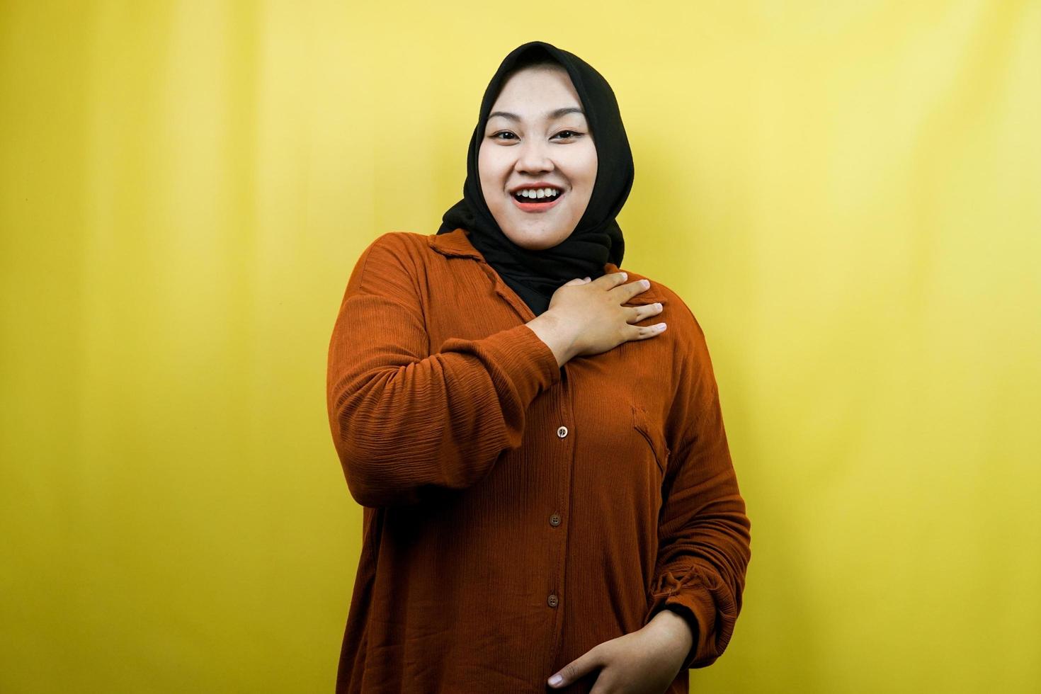 belle et joyeuse jeune femme musulmane asiatique avec les mains tenant la poitrine isolée photo